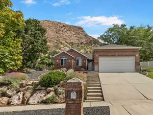 Ranch-style home with concrete driveway, a mountain view, brick siding, and a garage