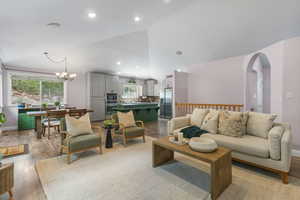 Living room featuring light wood finished floors, a chandelier, high vaulted ceiling, and recessed lighting