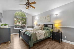 Bedroom with vaulted ceiling, wood finished floors, on suite bath with walk in closet and ceiling fan
