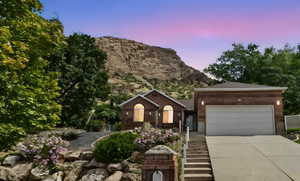 Ranch-style home featuring concrete driveway, an attached garage, a mountain view, and brick siding