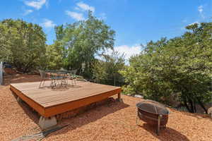 View of yard featuring a fire pit, a deck, view of wooded area, and outdoor dining area
