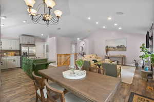 Dining room featuring vaulted ceiling, a chandelier, dark wood finished floors, and recessed lighting