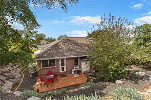 Back of house with a shingled roof, brick siding, and a deck