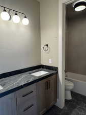 Bathroom with vanity, dark tile patterned flooring, and shower / bathtub combination