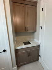 Bar featuring wood finish cabinetry and light stone countertops