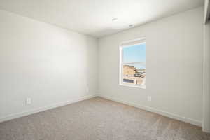 Carpeted spare room featuring baseboards