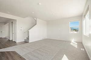 Unfurnished living room featuring stairway, dark wood-style flooring, and recessed lighting