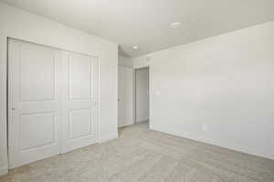 Unfurnished bedroom featuring light carpet and a closet