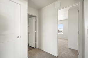 Hallway with light carpet and baseboards