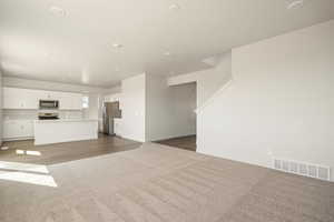 Unfurnished living room featuring dark colored carpet, recessed lighting, and dark wood-type flooring