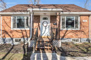 View of exterior entry featuring brick siding and roof with shingles