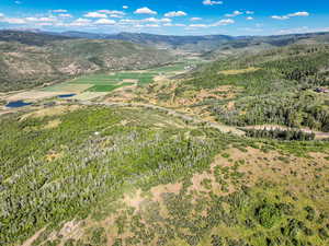 Aerial overview of property's location featuring a mountainous background and a forest