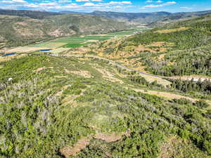Aerial view of property and surrounding area with a mountain backdrop and a heavily wooded area