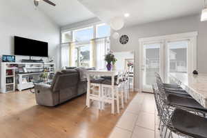 Living room featuring vaulted ceiling, ceiling fan, light tile patterned floors, and recessed lighting