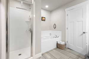 Bathroom with a stall shower, a garden tub, wood finish floors, and recessed lighting