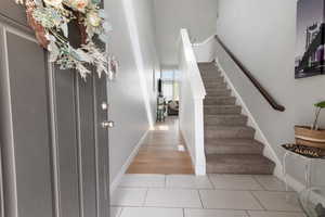 Entryway featuring light tile patterned flooring and stairway