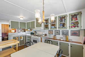 Kitchen with green cabinetry, white gas stove, and light countertops
