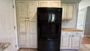 Kitchen featuring freestanding refrigerator, light tile patterned floors, wood counters, and light brown cabinets