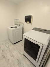 Laundry room with light marble finish flooring and washer and clothes dryer