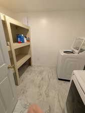 Laundry room featuring light marble finish flooring and separate washer and dryer