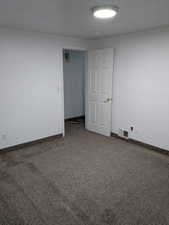 Carpeted spare room featuring baseboards and a textured ceiling