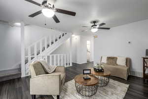 Living room with dark wood-style flooring, stairway, and a ceiling fan