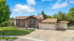 View of front of property featuring stone siding, concrete driveway, a garage, a chimney, and a shingled roof