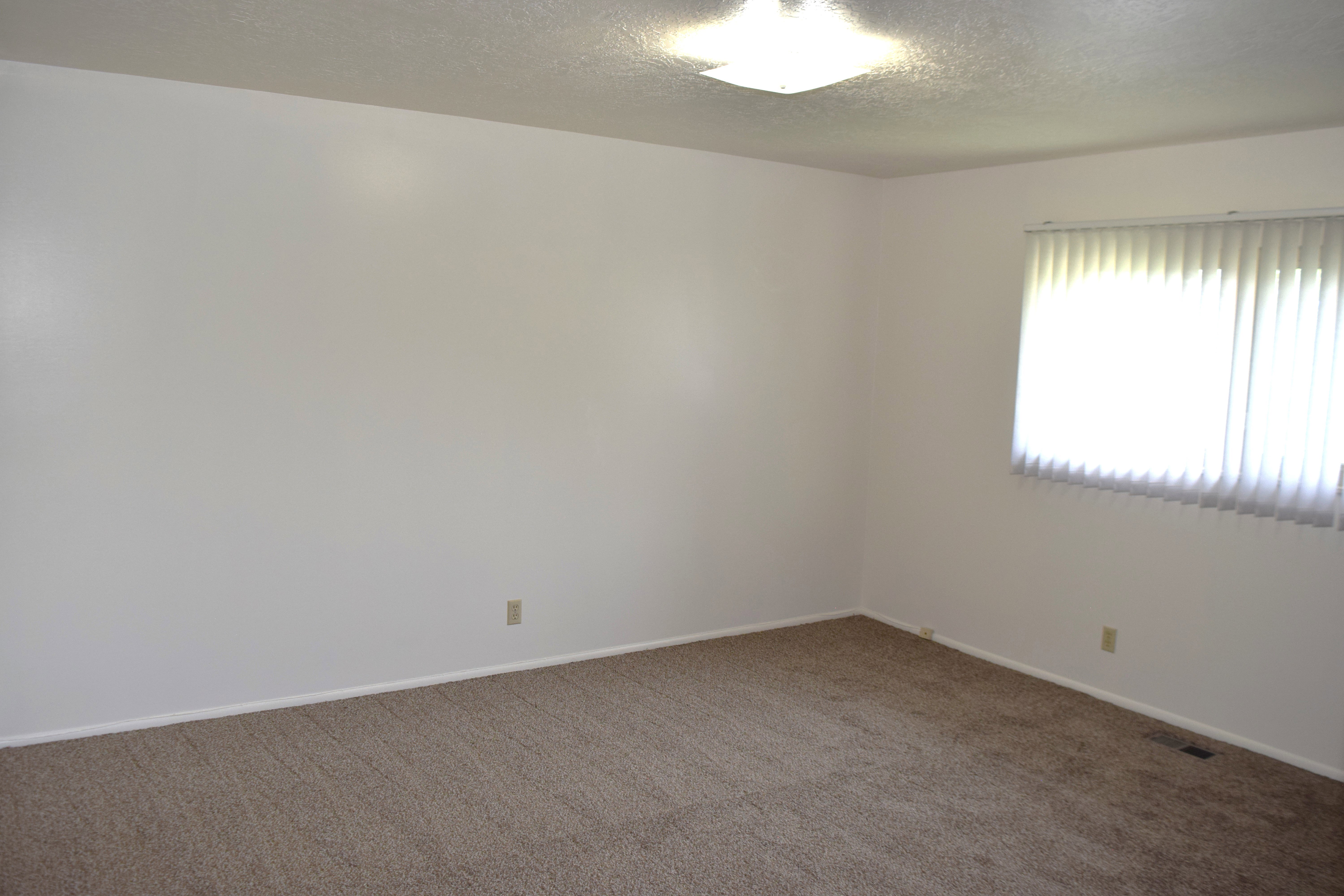 Carpeted empty room featuring a textured ceiling and baseboards