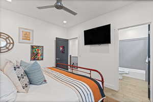 Bedroom featuring wood finished floors, a ceiling fan, recessed lighting, and ensuite bathroom