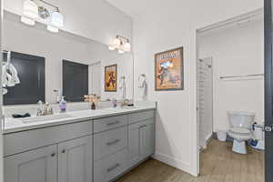 Bathroom with double vanity, wood tiled floors, and a tile shower