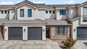 View of front of property featuring brick siding, an attached garage, and driveway