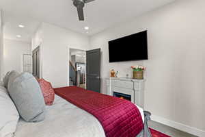 Bedroom featuring tile floors, ceiling fan, recessed lighting, and a warm lit fireplace