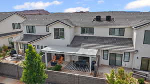 Rear view of property featuring a patio, stucco siding, a mountain view, and an outdoor living space with a fire pit