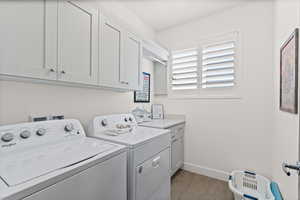 Laundry room featuring light tiel floors, washing machine and dryer, and cabinet space