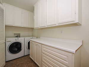 Laundry room with washing machine and dryer, dark tile patterned flooring, and cabinet space