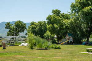 View of grassy yard featuring a playground and a mountain view