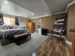 Bedroom featuring dark wood-style flooring, beam ceiling, a textured ceiling, recessed lighting, and crown molding