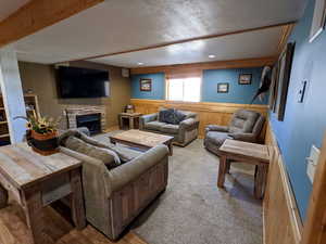 Carpeted living area featuring a fireplace, wood walls, a wainscoted wall, a textured ceiling, and recessed lighting