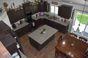 Kitchen with dark brown cabinets, black stainless steel appliances, and a kitchen island
