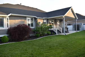Back of house with a shingled roof, a patio, stucco siding, and a shed