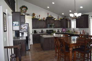 Kitchen featuring dark brown cabinetry, a kitchen island, granite counters, and lofted ceiling