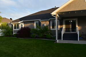 View back of house exterior with stucco siding, a yard, and covered patio