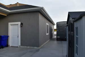 View of side of property with stucco siding and roof with shingles
