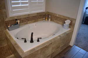 Ensuite bathroom featuring a Garden Tub, tiled tub surround woodgrain tile floors