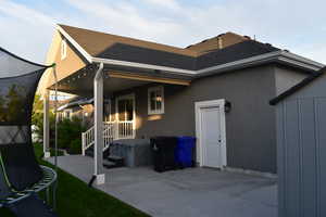 Back of house featuring a shingled roof, a patio area, and stucco siding