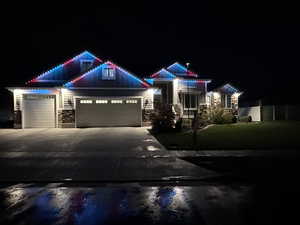 View of front of house featuring stone siding, an attached garage, driveway, and a yard