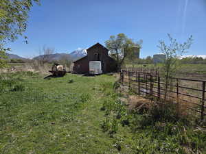 View of yard featuring a barn, an outdoor structure, a view of countryside, and a mountain view