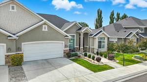 Craftsman-style house with stone siding, stucco siding, concrete driveway, and a garage
