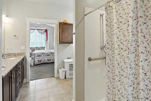 Ensuite bathroom featuring a shower stall, double vanity, and light tile patterned floors
