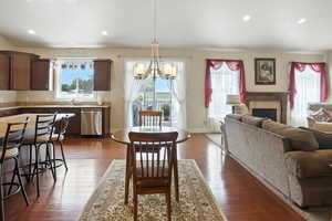 Dining space with a fireplace, recessed lighting, a chandelier, and dark wood-style floors